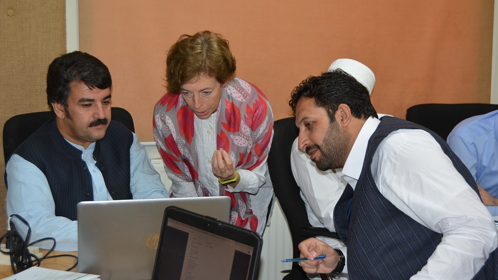 Colleagues gather around a laptop