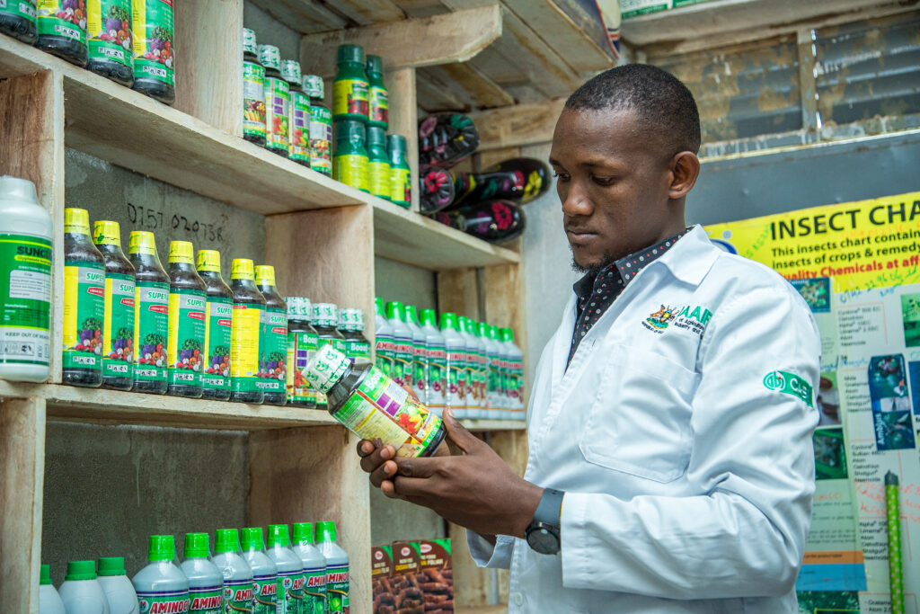 A young agro-dealer in Uganda, looks at his stock of pesticides, while in his shop