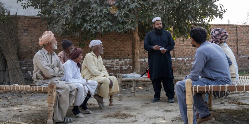 Agricultural officer, Muhammad Farooq, explains the trichogramma cards to a group of farmers