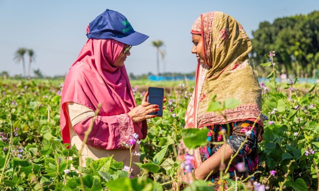A female extension officer showing a female farmer a digital device