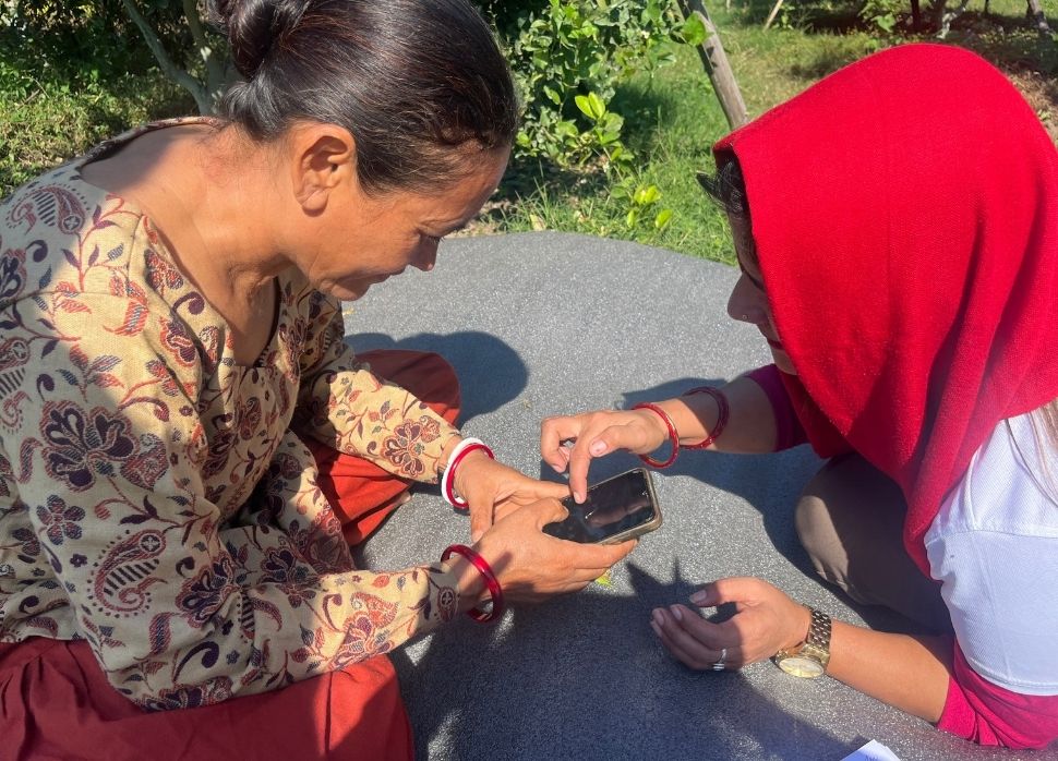 Women farmers using a mobile device.