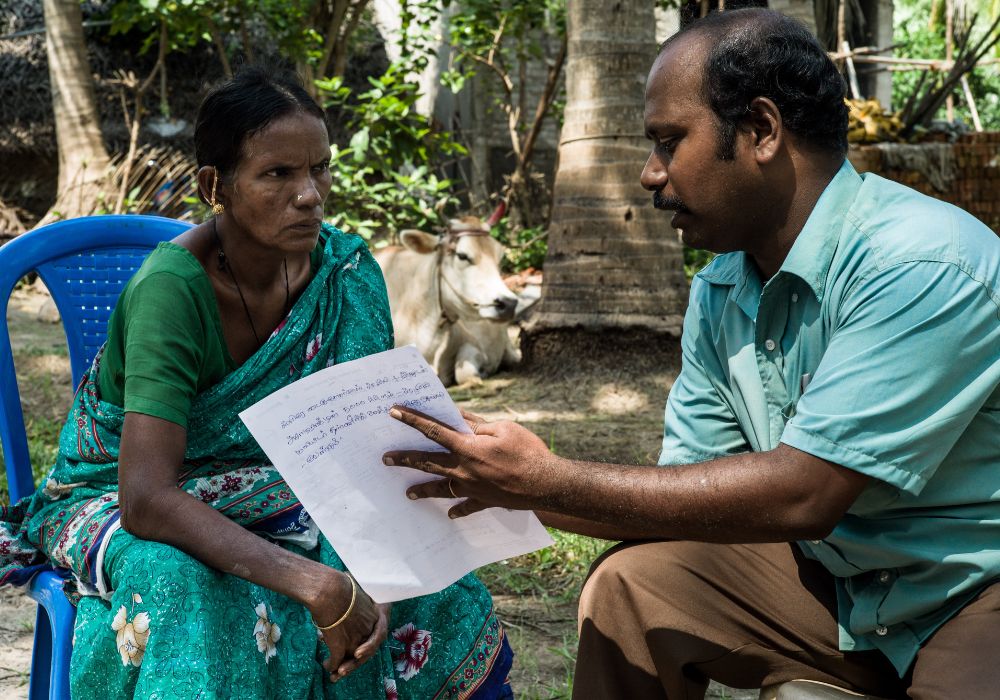 An agricultural extension worker providing crop health advice to a female farmer in India