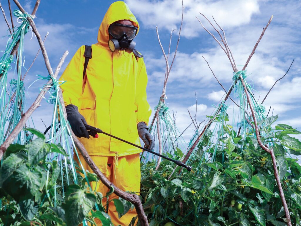 A spray service provider wearing protective clothing, gloves, goggles and a respirator while preparing pesticide spraying equipment in Kenya.